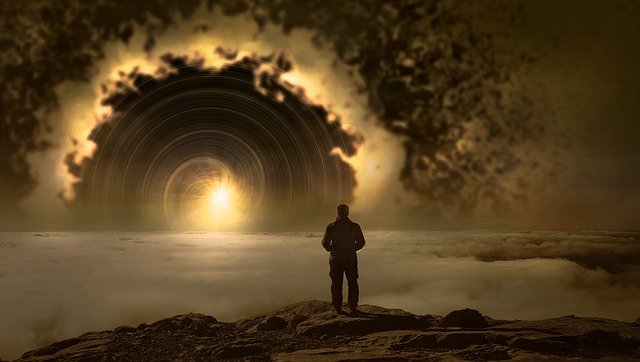 A man stands on a foggy shore looking into a whirlpool of clouds and light on the horizon